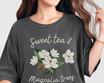 May include: A charcoal gray t-shirt with a white floral design and the text "Sweet tea & magnolia trees".