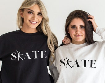 May include: Two women wearing black and white sweatshirts with the word "SKATE" and a figure skater graphic printed on the front.