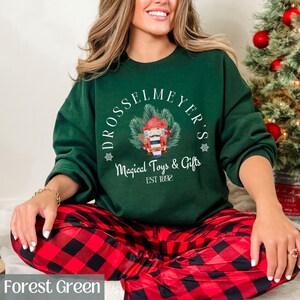May include: Forest green sweatshirt with a white graphic of a nutcracker holding a drum and a Christmas tree. The graphic also includes the text "Drosselmeyer's Magical Toys & Gifts Est 1892".