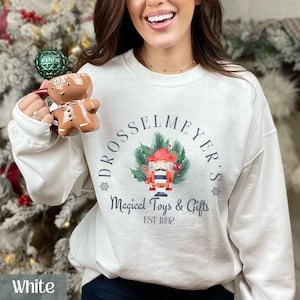 May include: White sweatshirt with a Christmas-themed design featuring a Nutcracker doll, a wreath of holly, and the text "Drosselmeyer's Magical Toys & Gifts Est 1892".