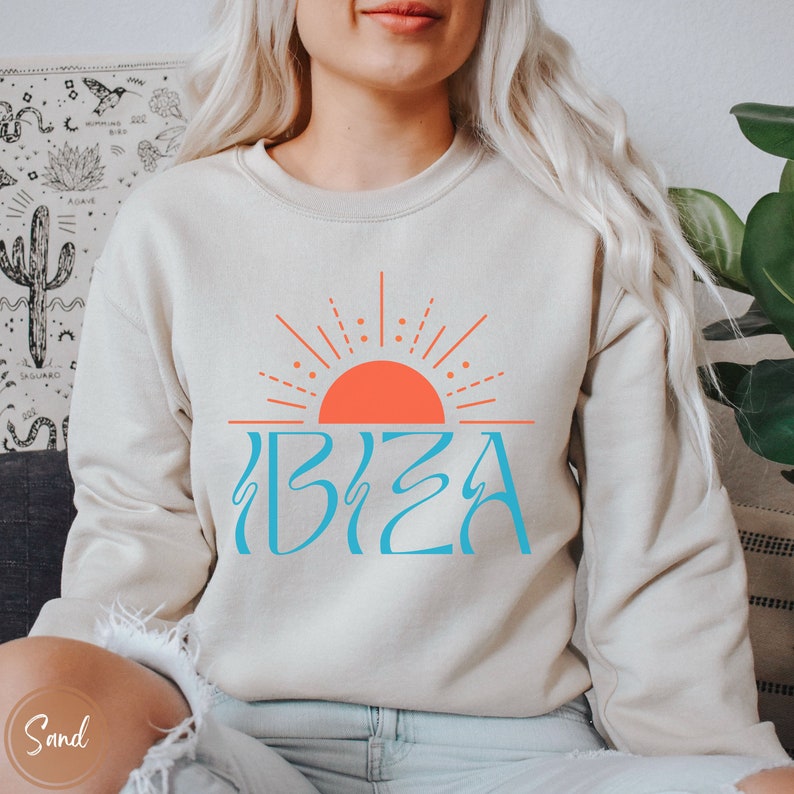 May include: A beige sweatshirt with a blue and orange graphic of a sun and the word "IBIZA" on the front.