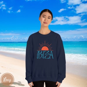 May include: A navy blue sweatshirt featuring a graphic of a stylised sun and the word "IBIZA" in a blue and orange colour scheme.