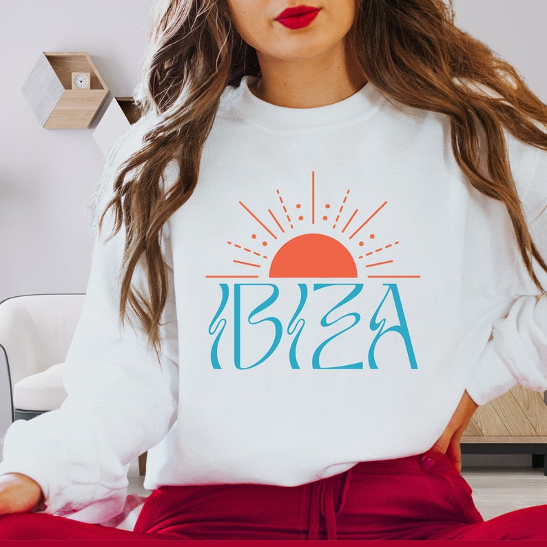 May include: White sweatshirt with a blue and orange graphic of a sun and the word "IBIZA" on it.