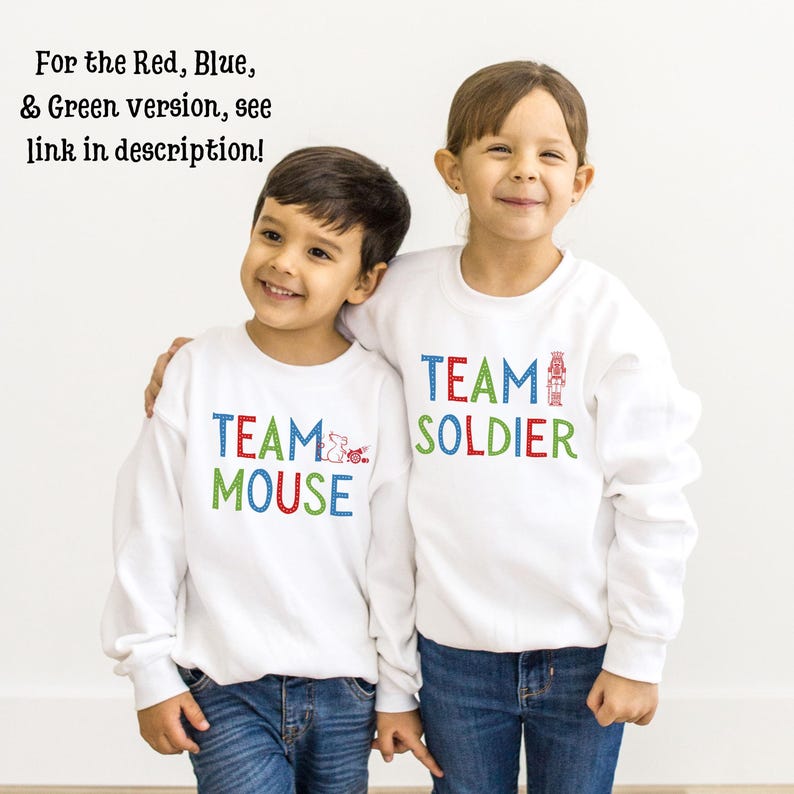 May include: Two children wearing white sweatshirts with colorful text. The boy's sweatshirt says "TEAM MOUSE" and the girl's sweatshirt says "TEAM SOLDIER".