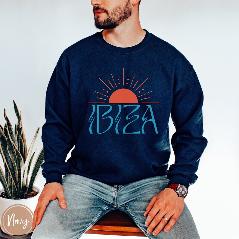 May include: A navy blue sweatshirt featuring a graphic of a stylised sun and the word "IBIZA" in a blue font.