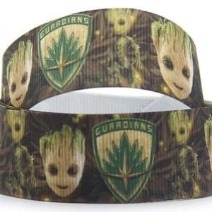May include: A decorative ribbon featuring a repeating pattern of the character Groot from Guardians of the Galaxy. The ribbon also includes the Guardians logo in green and gold, with the word "GUARDIANS" at the top.