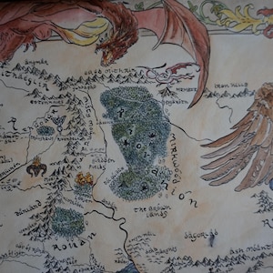 May include: A hand-drawn fantasy map on parchment paper featuring a large red dragon flying across the top and a brown eagle on the right side. The map displays various geographical locations, mountain ranges, and forests with black ink text labels.