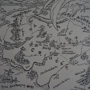 May include: A black and white ink illustration of a fantasy map featuring geographical regions labeled Ered Luin, The Shire, and Minhiriath. The map includes detailed drawings of mountain ranges, forests, and a sailing ship in The Sundering Seas.