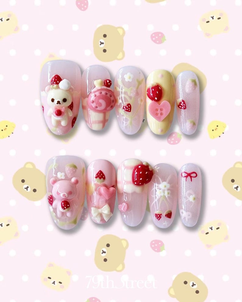 May include: A set of ten artificial nails with a pink and white strawberry and bear theme. The nails feature 3D designs of strawberries, hearts, bows, and bears. The background is a pink pattern with bears and strawberries.