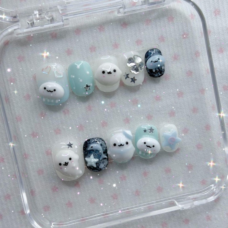 Peut inclure: Un ensemble de dix faux ongles dans un &eacute;tui en plastique transparent. Les ongles pr&eacute;sentent divers motifs, notamment des personnages de dessins anim&eacute;s, des &eacute;toiles et des pois, dans des tons de bleu, de blanc et de noir. Les ongles sont ovales et ont une finition brillante.