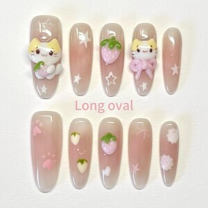 May include: Set of ten long oval false nails with various cute designs. The designs include a cat with a strawberry, a strawberry, a star, a paw print, and a flower.