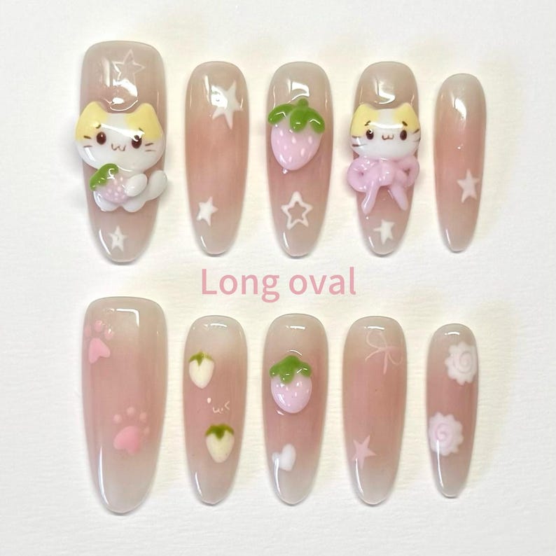 May include: Set of ten long oval false nails with various cute designs. The designs include a cat with a strawberry, a strawberry, a star, a paw print, and a flower.