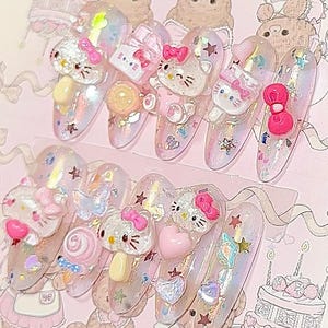 Peut inclure: Dix faux ongles longs et ovales. Chaque ongle est d&eacute;cor&eacute; de paillettes roses, blanches et iris&eacute;es, ainsi que d'ornements 3D comprenant des figurines Hello Kitty, des n&oelig;uds, des c&oelig;urs et des &eacute;toiles. Le th&egrave;me g&eacute;n&eacute;ral est mignon et girly.