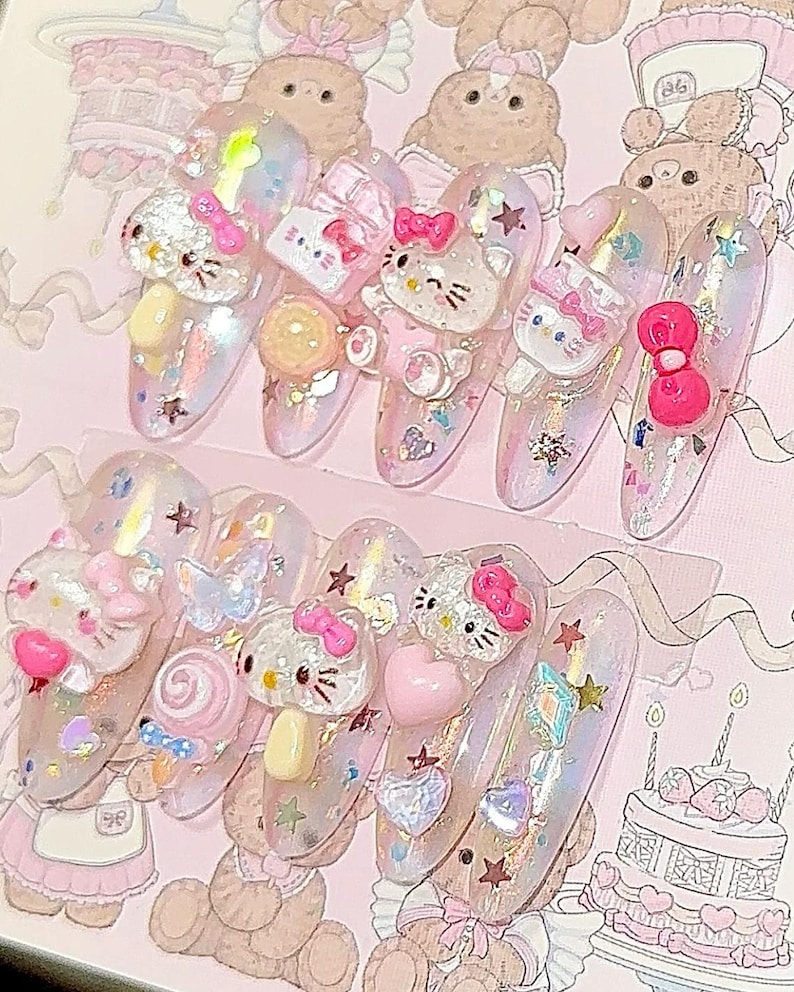 Peut inclure: Dix faux ongles longs et ovales. Chaque ongle est d&eacute;cor&eacute; de paillettes roses, blanches et iris&eacute;es, ainsi que d'ornements 3D comprenant des figurines Hello Kitty, des n&oelig;uds, des c&oelig;urs et des &eacute;toiles. Le th&egrave;me g&eacute;n&eacute;ral est mignon et girly.