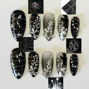 May include: Set of ten black and white press-on nails with silver accents. The nails feature a variety of designs, including crosses, stars, and fleur-de-lis.