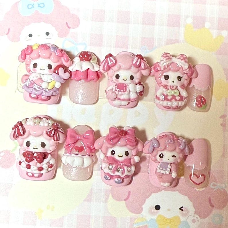 Puede incluir: Una colecci&oacute;n de dise&ntilde;os de u&ntilde;as rosas y blancos con personajes de dibujos animados. Los dise&ntilde;os incluyen figuras en miniatura, lazos y detalles de coraz&oacute;n. Las u&ntilde;as est&aacute;n dispuestas sobre un fondo a cuadros rosa y blanco.