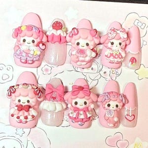 Puede incluir: Un conjunto de u&ntilde;as postizas rosas con varios dise&ntilde;os 3D. Los dise&ntilde;os incluyen personajes de dibujos animados, lazos y acentos de fresas. Algunas u&ntilde;as tienen purpurina y detalles de coraz&oacute;n, creando una est&eacute;tica linda y juguetona.