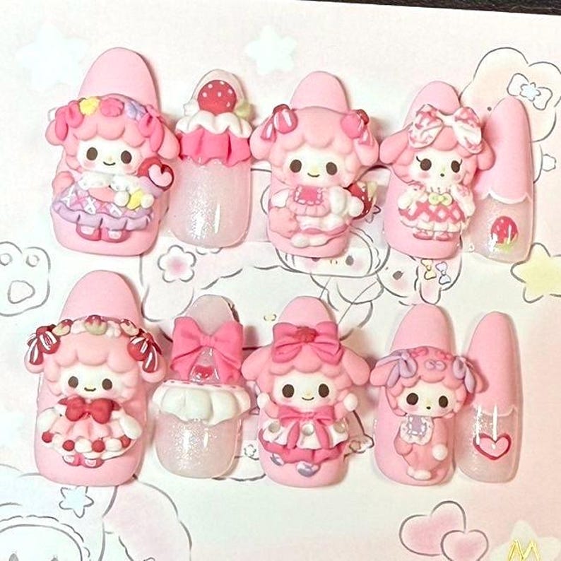 Puede incluir: Un conjunto de u&ntilde;as postizas rosas con varios dise&ntilde;os 3D. Los dise&ntilde;os incluyen personajes de dibujos animados, lazos y acentos de fresas. Algunas u&ntilde;as tienen purpurina y detalles de coraz&oacute;n, creando una est&eacute;tica linda y juguetona.