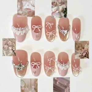 K&ouml;nnte beinhalten: Rosa und wei&szlig;e Nagelkunst mit Perlen- und Strass-Akzenten. Die N&auml;gel haben Schleifen, R&uuml;schen und Glitzer.