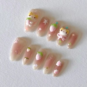 May include: Set of ten nude-colored false nails with various 3D decorations, including strawberries, stars, and cartoon cats.