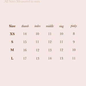 May include: A nail size guide from 79th Street, with measurements in millimeters. The guide lists sizes XS, S, M, and L, with corresponding thumb, index, middle, ring, and pinky measurements. The text is in a serif font on a light beige background.