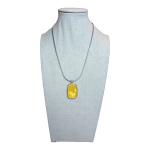 May include: A silver chain necklace with a yellow rectangular pendant. The pendant has a smooth, shiny surface.
