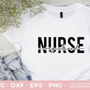 May include: White t-shirt with black text that reads "NURSE registered" in a bold, stylized font. The shirt is laying flat on a wooden surface with a pair of blue jeans and white flowers.