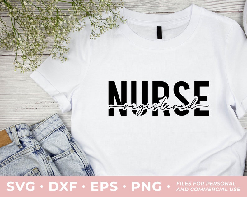 May include: White t-shirt with black text that reads "NURSE registered" in a bold, stylized font. The shirt is laying flat on a wooden surface with a pair of blue jeans and white flowers.