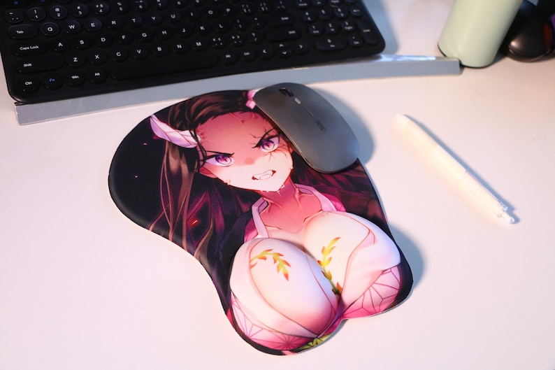 May include: A pink and white anime-style wrist rest with a female character with long black hair and a pink and white outfit. The wrist rest is on a white surface with a computer mouse and a pen.