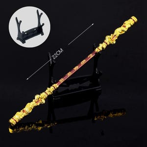 K&ouml;nnte beinhalten: Eine goldene und rote dekorative Lanze mit chinesischen Schriftzeichen auf dem Schaft, 56 cm lang, auf einem schwarzen St&auml;nder ausgestellt.