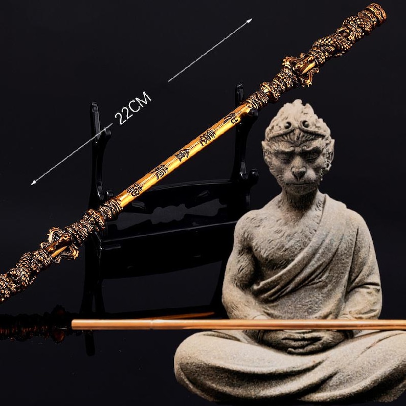 K&ouml;nnte beinhalten: Ein goldfarbener Stab mit chinesischen Schriftzeichen und einer Affenfigur, die in meditativer Pose sitzt. Der Stab ist 56 cm lang.
