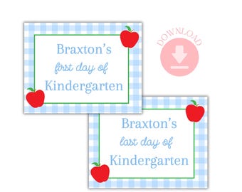 May include: Two rectangular signs with a blue and white gingham pattern. The signs have a green border and red apple illustrations. One sign reads "Braxton's first day of Kindergarten" and the other reads "Braxton's last day of Kindergarten".