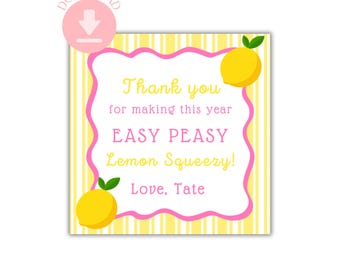 May include: A pink and yellow thank you card with a lemon design. The card says "Thank you for making this year easy peasy lemon squeezy! Love, Tate."