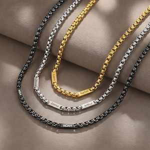 May include: Three personalized box chain necklaces in black, silver, and gold. Each necklace features a nameplate with a name engraved on it. The names include Mia, Olivia, Noah, Liam, Rachel, Emma, and Arthur.