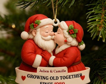 May include: A Christmas tree ornament depicting Santa Claus and Mrs. Claus kissing. They wear red suits with white detailing and holly-decorated hats. The banner reads "Julien & Camille GROWING OLD TOGETHER SINCE 1980."