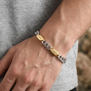 Puede incluir: Una pulsera de cadena de plata con dos placas rectangulares doradas grabadas con los nombres "Lacy" y "Hamm". La pulsera se lleva en la muñeca.