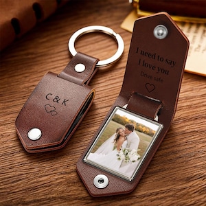 May include: Two brown leather keychains with silver metal rings. One is closed, showing the text C&K and two hearts. The other is open, revealing a photograph of a couple and the text I need to say I love you Drive safe with a heart symbol.