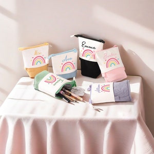 May include: Six colorful pencil cases with rainbow and heart designs. Each case has a different name on it: Ava, Mix, Emma, Barbie, Allison, and Taylor.