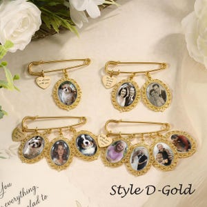 May include: Four gold-toned safety pins featuring oval photo frames with ornate filigree edges. Each pin includes a small heart-shaped charm engraved with text. The pins display various photographs of people and pets, arranged in a decorative display.