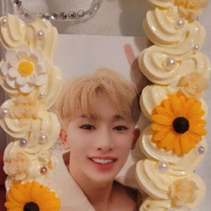 Peut inclure: Une coque de t&eacute;l&eacute;phone transparente d&eacute;cor&eacute;e de fleurs blanches et jaunes, d'un motif en spirale blanc et jaune, et d'une photo d'un jeune homme.