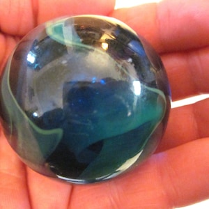 May include: A blue, green, and white marble with swirling patterns. The marble is round and has a glossy finish.