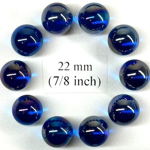 May include: A collection of ten iridescent blue glass marbles, each approximately 7/8 inch in diameter. The marbles have a glossy finish and reflect a range of colors. The text on the image indicates the marbles are 22 mm in size.