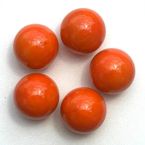 May include: Five glossy, orange-colored, spherical beads are arranged against a white background. The beads have a smooth, reflective surface, and their color is consistent throughout. The arrangement suggests a focus on jewelry making or crafting.