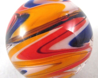 May include: A clear glass marble with a swirl design. The marble features vibrant colors including red, orange, blue, and black. The colors are swirled together in a dynamic pattern. The marble is round and has a glossy finish.
