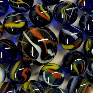 Könnte beinhalten: Eine Sammlung von Glasmurmeln in verschiedenen Größen und Designs. Die Murmeln weisen wirbelnde Muster in Blau, Weiß, Gelb und Rot auf. Die glänzenden Oberflächen reflektieren das Licht und erzeugen eine lebendige und verspielte Darstellung. Diese Murmeln sind ideal für Sammler oder zum Spielen.