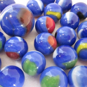 May include: A collection of blue marbles with white, red, yellow, and green swirls. The marbles are arranged in a random pattern on a white surface.