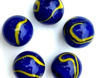 May include: Five blue marbles with yellow swirling patterns. Each glass marble has a glossy finish. The marbles are arranged in a circular pattern against a white background. These marbles are a classic toy.