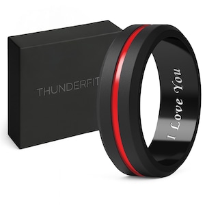 May include: Black ring with a red stripe and the engraved text "I Love You." The ring is next to a black box with the word "THUNDERFIT" printed on it. The ring is a modern design.