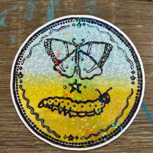 K&ouml;nnte beinhalten: Ein runder Aufkleber mit holografischem Finish zeigt eine Schwarzwei&szlig;illustration eines Schmetterlings und einer Raupe. Der Hintergrund ist ein Farbverlauf von Blau zu Gelb.