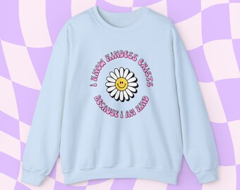 May include: Light blue sweatshirt with a pink daisy graphic and the text "I know kindness exists because I am kind".